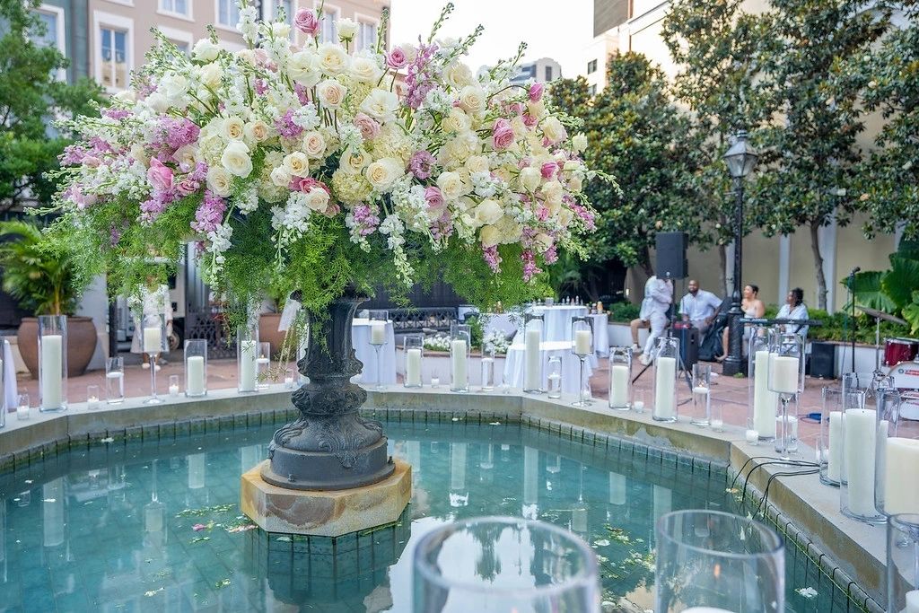A large vase of flowers in the middle of a fountain.