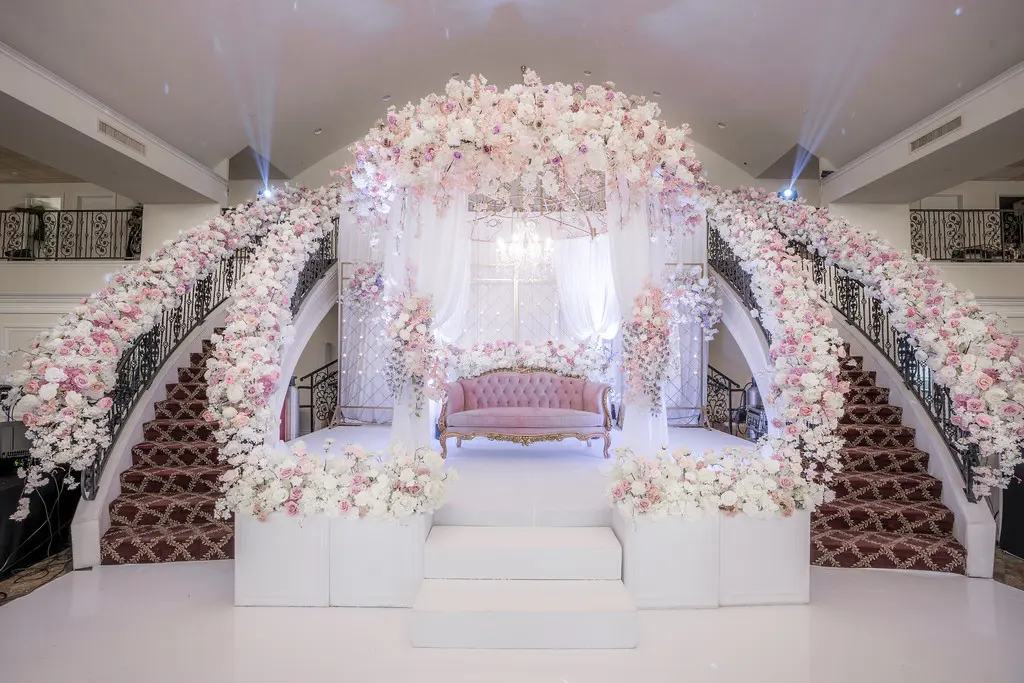 A wedding ceremony with pink flowers and white furniture.