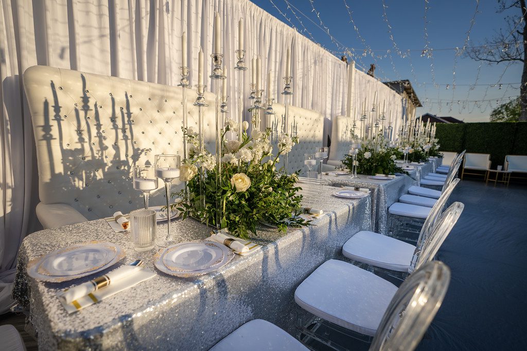 A long table with white chairs and flowers on it