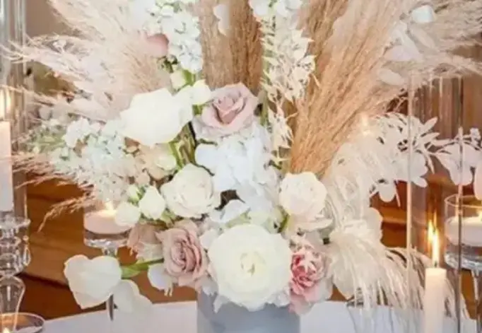 A bouquet of flowers in a vase with some feathers.