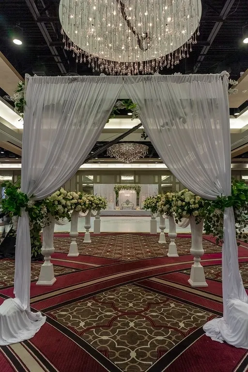 A wedding ceremony with white drapes and flowers.